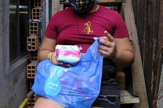 Mulher com sacola de absorventes, item de higiene básica para a saúde feminina. (Foto: Arquivo/Unicef Brasil)