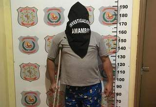 Adriano ao ser apresentado pela polícia, apoiado em muleta e capuz na cabeça (Foto: Divulgação)
