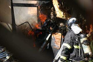 Bombeiro controlando foco de incêndio dentro da casa. (Foto: Henrique Kawaminami)