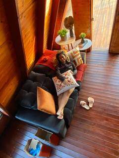 Fabiana Benites deitada no sofá que tem dentro da cabana. (Foto: Arquivo pessoal)