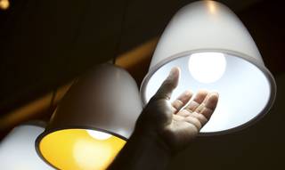 Homem confere lâmpada. Custo extra da energia se manterá em patamar alto (Foto: Agência Brasil)