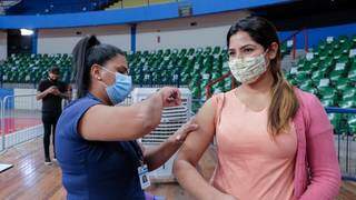 Mulher recebe dose da vacina no ginásio Guanandizão. (Foto: PMCG)