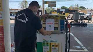 Fiscal do Procon MS fixando placa de interdição na bomba de etanol. (Foto: Divulgação)