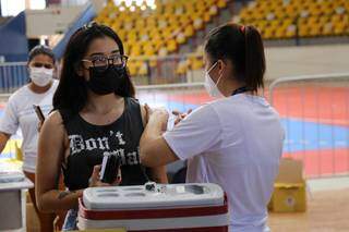 Jovem é vacinada em posto montado no ginásio Guanandizão. (Foto: Paulo Francis)