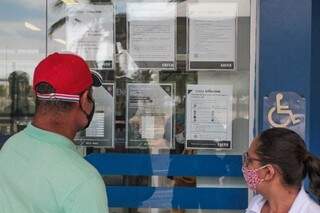 Beneficiários observam calendário em frente de agência em Campo Grande (Foto: Arquivo)