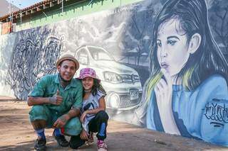 Sanderlei e sua filha com arte em grafite no Bairro Caiçara. (Foto: Henrique Kawaminami)