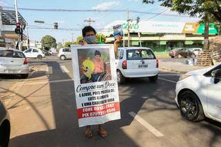 Com banner, ela pede ajudar de quem para no semáforo. (Foto: Paulo Francis)