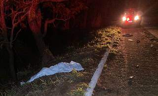 Corpo de homem atropelado encoberto por lençol, em beira de rodovia. (Foto: Jornal da Nova)