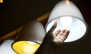 Homem confere lâmpada: custo extra da energia se manterá em patamar alto (Foto: Agência Brasil/Arquivo)