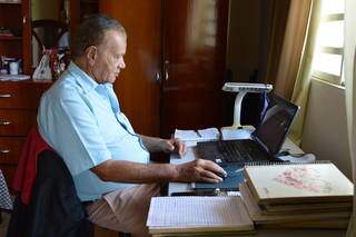 Seu Renan em seu &#34;escritório&#34; com parte dos cadernos e computador. (Foto: Bárbara Cavalcanti)