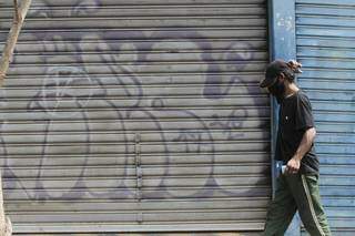 De máscara, homem caminha em frente a loja fechada no Centro de Campo Grande (Foto: Marcos Maluf)