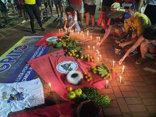 Após colocar frutas e verduras sobre bandeiras do MST, manifestantes acenderam velas pelas vítimas da covid-19. (Foto: Caroline Maldonado)