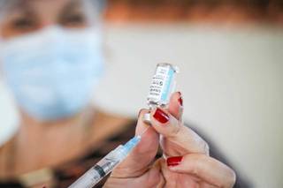 Profissional da saúde se preparando para aplicar mais uma dose de vacina (Foto: Henrique Kawaminami)