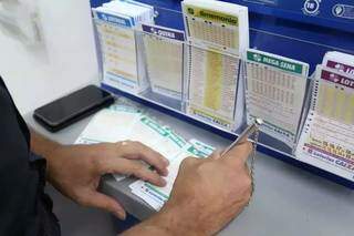 Apostador anota dezenas em cartão da Mega-Sena. (Foto: Arquivo / Campo Grande News)