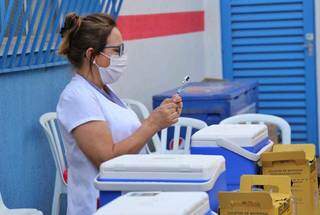 Profissional da saúde manuseando vacina contra a covid-19, em ponto de imunização de Campo Grande. (Foto: Paulo Francis)