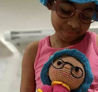 Segurando uma boneca de crochê inspirada nela mesma, Geovana teve sua história contada nas redes sociais. (Foto: Arquivo Pessoal)