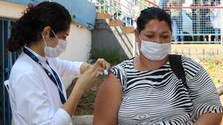 Profissional de saúde vacina mulher em posto de Campo Grande. (Foto: PMCG)