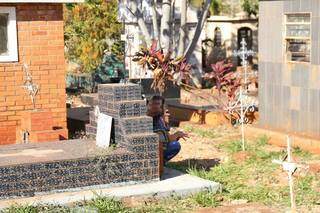 Jovem reza na sombra de túmulo em cemitério da Capital (Foto: Arquivo)