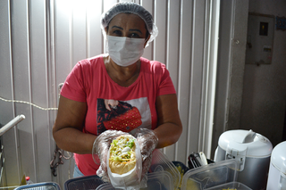 Tia Lourdes preparando um dos hot dogs para um cliente. (Foto: Bárbara Cavalcanti)