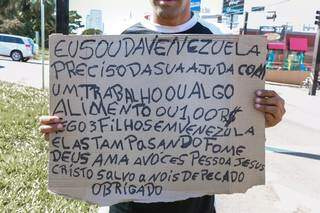 Venezuelano segura cartaz em que pede trabalho, comida ou dinheiro para ele e os filhos (Foto: Henrique Kawaminami/Arquivo)
