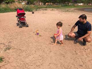 Ao lado do pai Daniel, Isis brinca na faixa de areia aberta pelo recuo da água. (Foto: Mariely Barros)