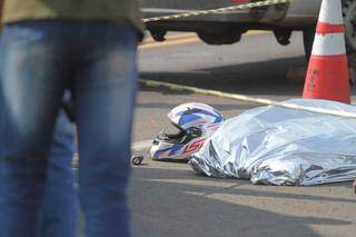 Capacete e corpo coberto de motociclista, que morreu após colidir na traseira de van. (Foto: Marcos Maluf)