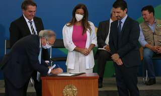 Presidente Jair Bolsonaro (à esquerda), observa o ministro da Economia, Paulo Guedes, assinar decreto que institui a Cédula de Produtor Rural. Foto: Agência Brasil