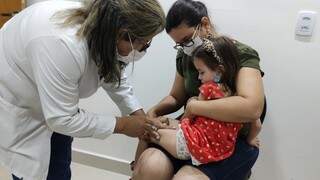 Menina é vacinada em unidade de saúde da Capital. (Foto: PMCG)