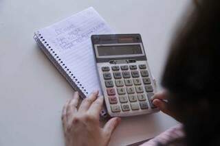 Calculadora sendo utilizada para cálculos de dívidas pessoais. (Foto: Kísie Ainoã)