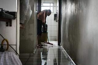 Morador puxa água que invadiu sua casa. (Foto: Marcos Maluf)