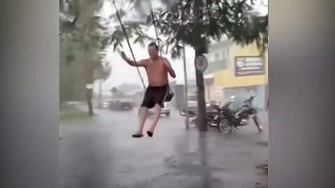 Feliz da vida, homem curte chuva em balanço na Av. Presidente Vargas