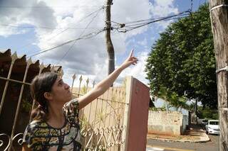 Dielle Costa, de 31 anos, aponta para cabos soltos em poste de madeira. (Foto: Kísie Ainoã)