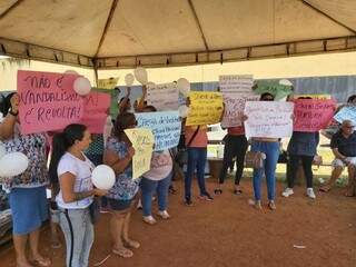 Familiares com cartazes durante manifestação em frente à penitenciária nesta segunda-feira (8). (Foto: Direto das Ruas)