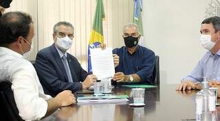 Reinaldo e Paulo Corrêa exibindo assinatura de documento que vai conceder benefícios aos motoristas de MS. (Foto: Chico Ribeiro/Divulgação/GovMS)