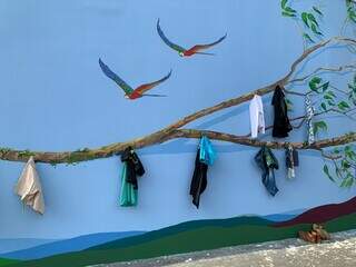 Ganchos foram colocados sobre pintura e doações podem ser penduradas no muro. (Foto: Divulgação)