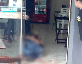Empresário caído na porta de padaria após ser baleado por assaltantes em Ponta Porã. (Foto: Direto das Ruas)