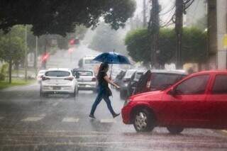 Mulher tenta escapar da chuva no início da manhã desta quarta. (Foto: Marcos Maluf)
