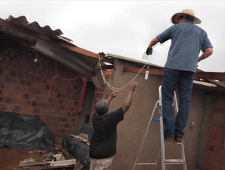 Moradores improvisando cobertura de residência após tempestade. (Foto: Divulgação)