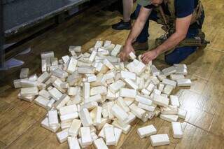Policial diante da centena de tabletes de cocaína apreendidos no endereço. (Foto: Divulgação) 