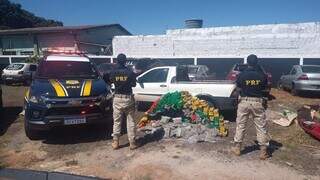 Policiais diante dos tabletes de maconha encontrados no veículo. (Foto: PRF)