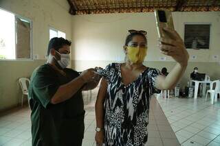 Mulher tira foto enquanto recebe terceira dose da vacina contra a covid. (Foto: Kísie Ainoã)