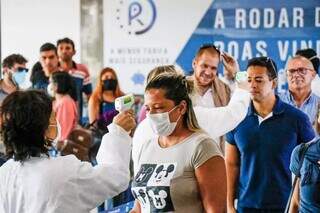 Agentes da vigilância sanitária medindo a temperatura de passageiros que acabavam de desembarcar em Campo Grande, em março do ano passado; máscaras ainda não eram obrigatórias (Foto: Henrique Kawaminami/Arquivo)