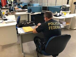 Agente da Polícia Federal vasculha documentos em escritório de contabilidade em Dourados. (Foto: Divulgação)