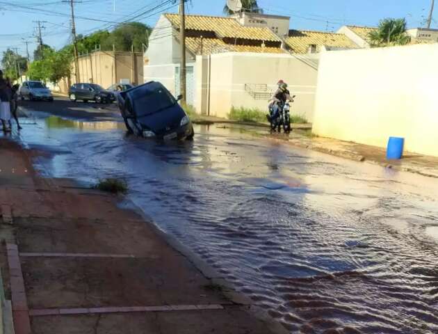 Cano estoura, abre cratera e carro fica suspenso em avenida movimentada