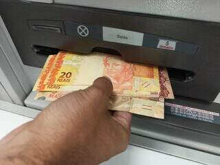 Homem saca dinheiro de caixa eletrônico, em um banco da Capital. (Foto: Kísie Ainoã)