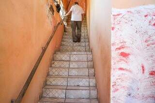 Raimundo subindo a escada para ter acesso a varanda que fica no piso superior da casa. (Foto: Henrique Kawaminami)