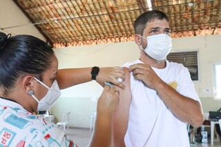 Profissional de saúde aplica de dose de vacina em braço de rapaz na Seleta. (Foto: Henrique Kawaminami)