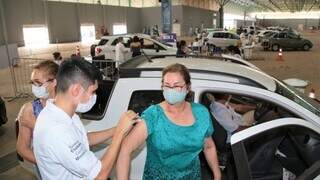 Mulher recebe dose da vacina em drive-thru de Campo Grande. (Foto: PMCG)