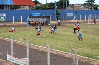 Lance da partida entre Coxim, de uniforme branco e vermelho, e Moreninhas, de azul (Foto: Esporte MS)
