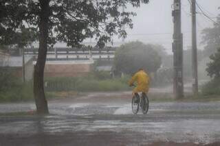 Ciclista da Capital se protegendo da chuva utilizando uma capa (Foto: Henrique Kawaminami)